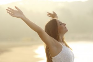 Relaxed woman breathing fresh air raising arms at sunrise